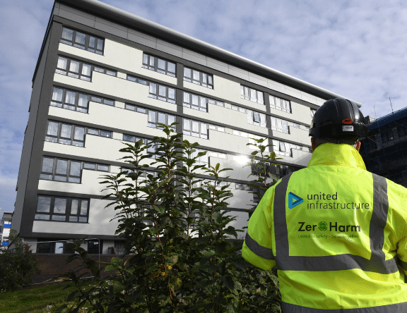 outside view of residential high rise building with united infrastructure employee standing in front